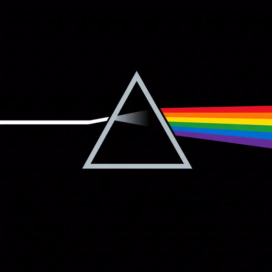 A white beam enters a glass prism on black and leaves as a rainbow.